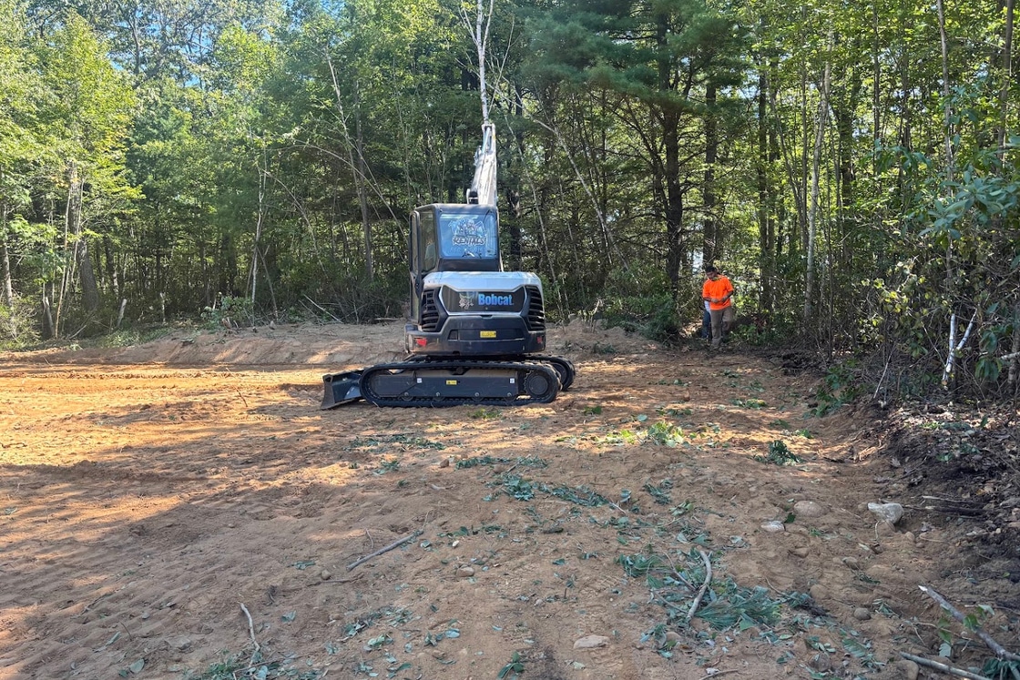 Bobcat excavator clearing brush and stumps on a wooded property
