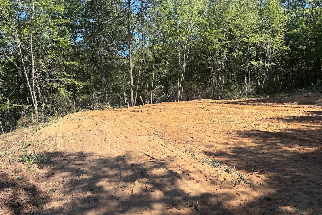 Cleared and graded building lot surrounded by mature trees after land clearing