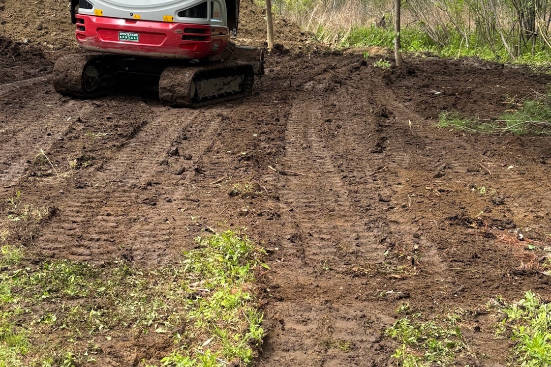 Mini excavator finishing rough grading on a cleared lot