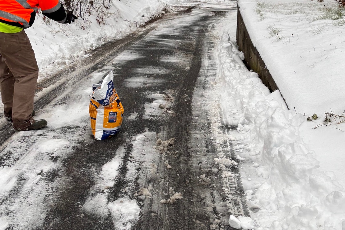Crew member spreading ice melt on a cleared residential driveway