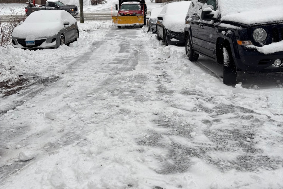 Plow truck clearing a snow covered driveway during a Connecticut snowstorm
