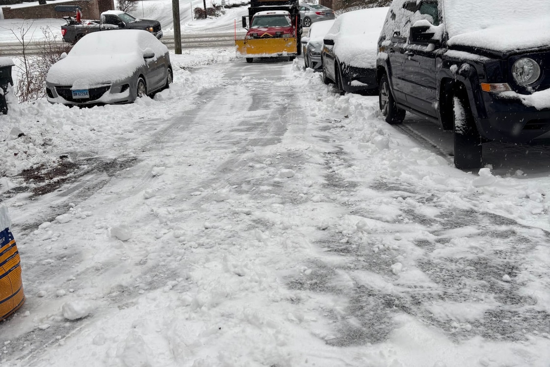 Snow plow truck working through heavy snow on a residential street