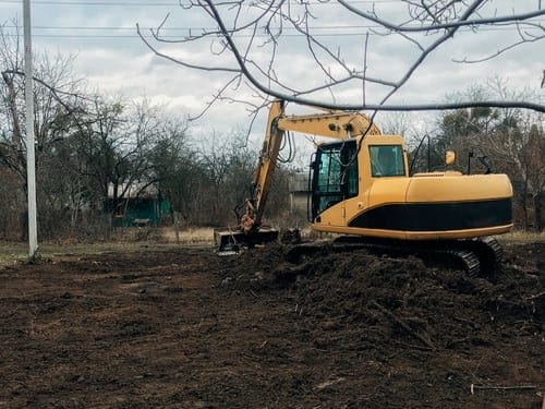 Excavator clearing brush and stumps from an overgrown building lot in Torrington, Connecticut